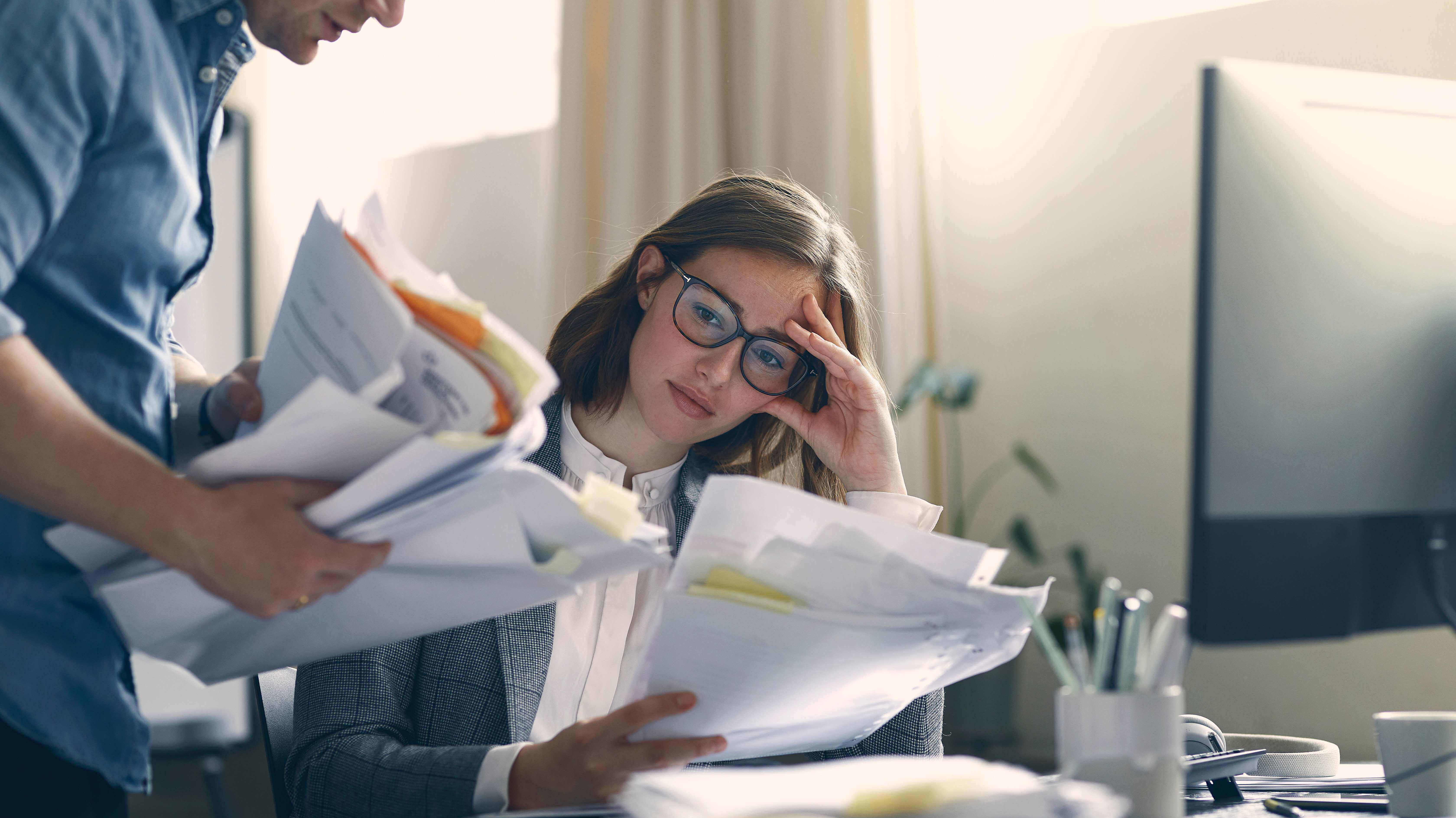 Eine Frau mit Brille schaut sich mit ihrem Kollegen Gesetze zum Arbeitsrecht an