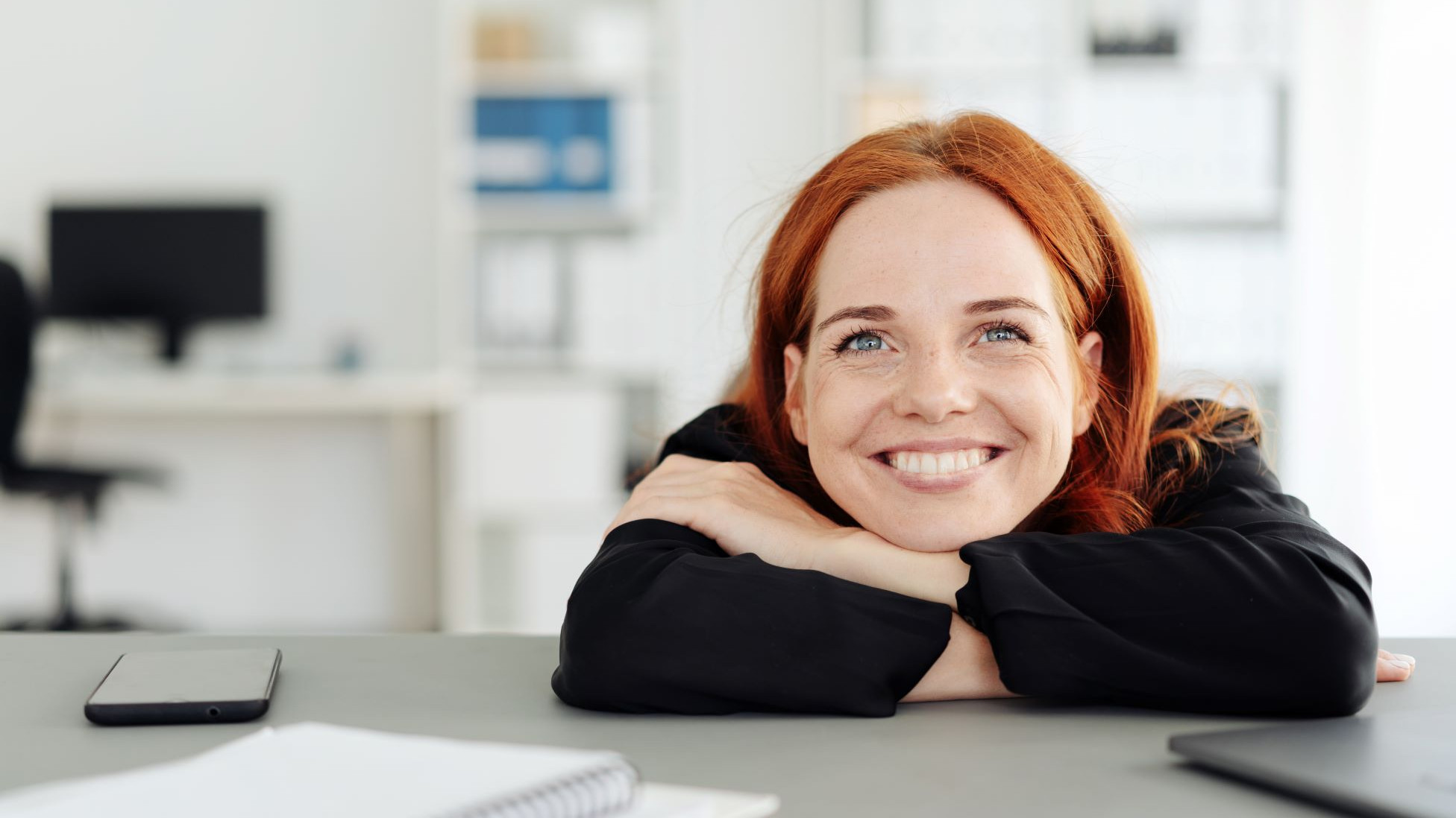 Eine Frau schaut grinsend und freut sich dass sie ihren Traumjob gefunden hat