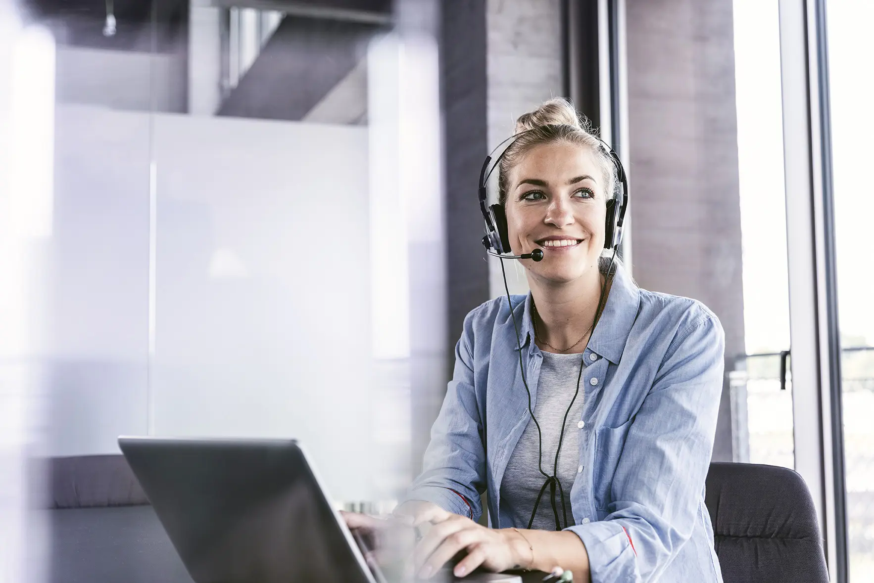 Eine Frau telefoniert mit Headset am Arbeitsplatz