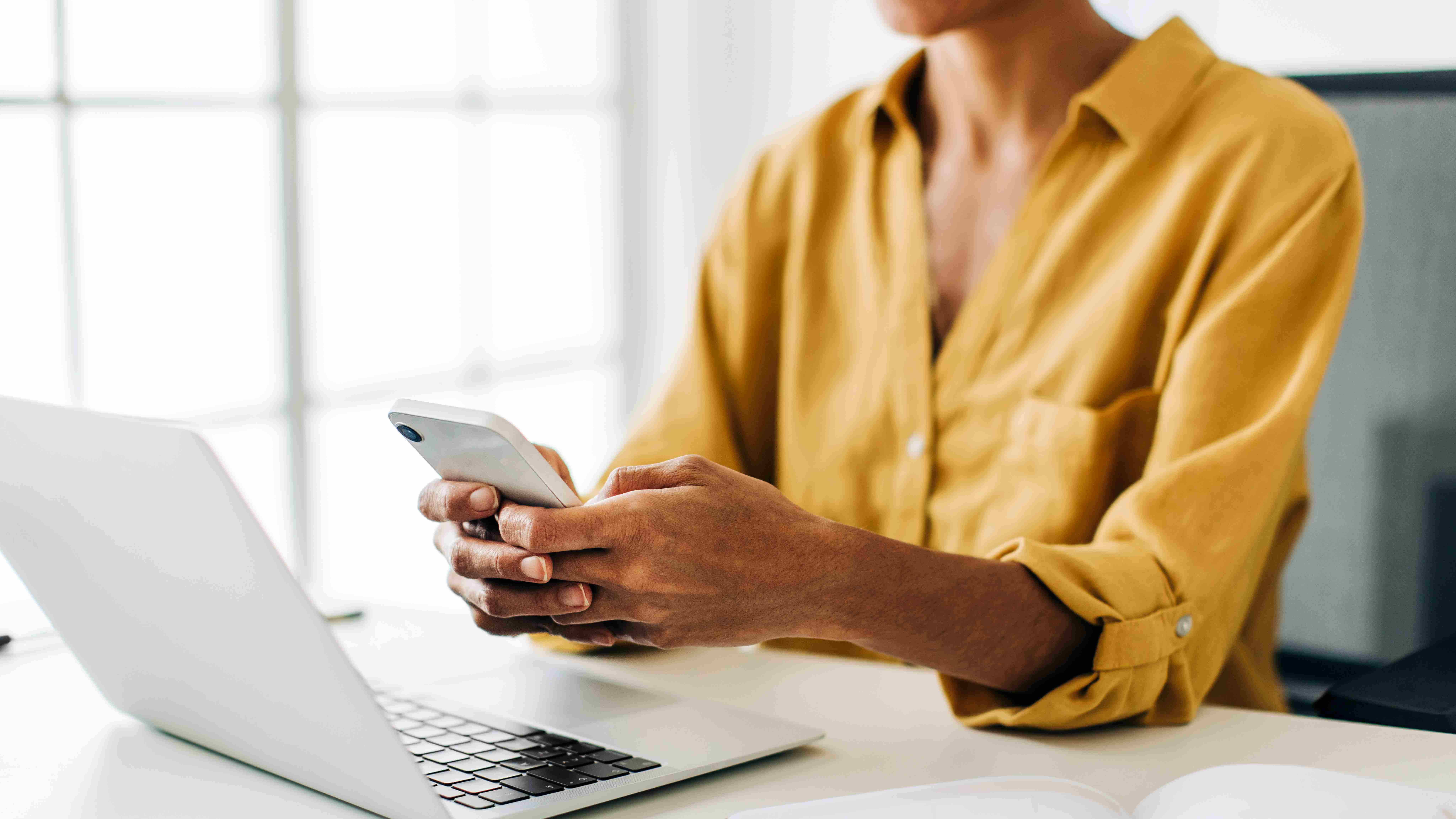 Eine Frau schaut am Schreibtisch auf ihr Smartphone