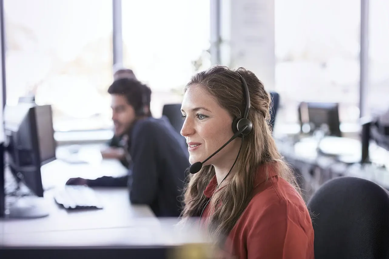 Eine Frau telefoniert mit Headset am Arbeitsplatz