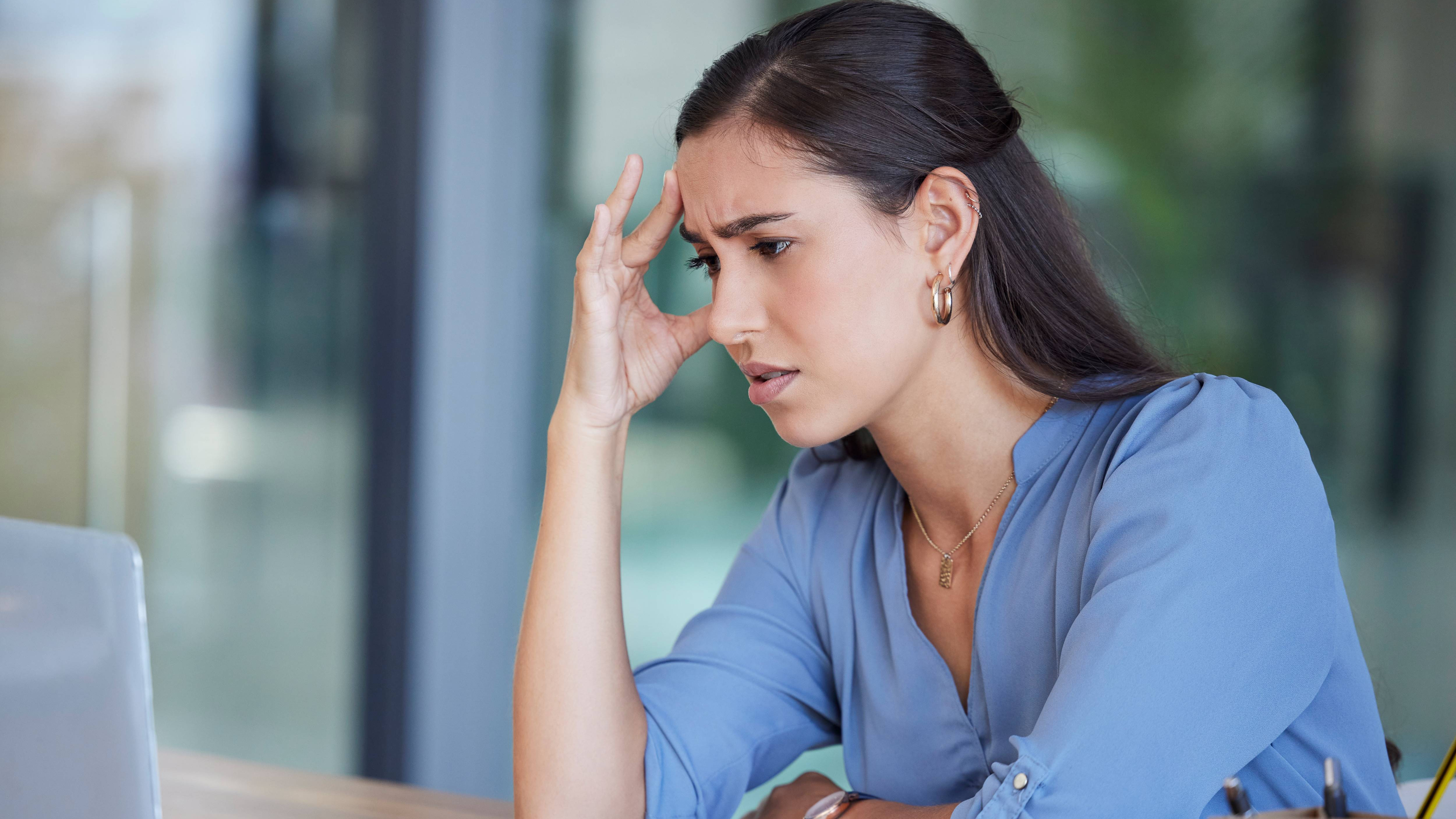 Eine Frau sitzt verzweifelt am Arbeitsplatz