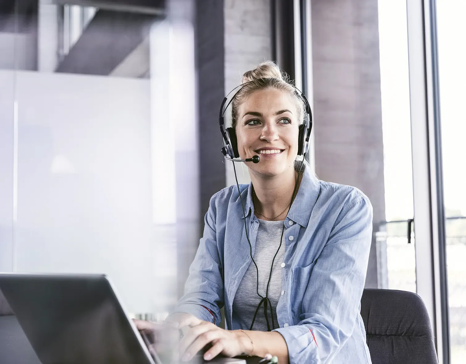 Eine Frau telefoniert mit Headset am Arbeitsplatz