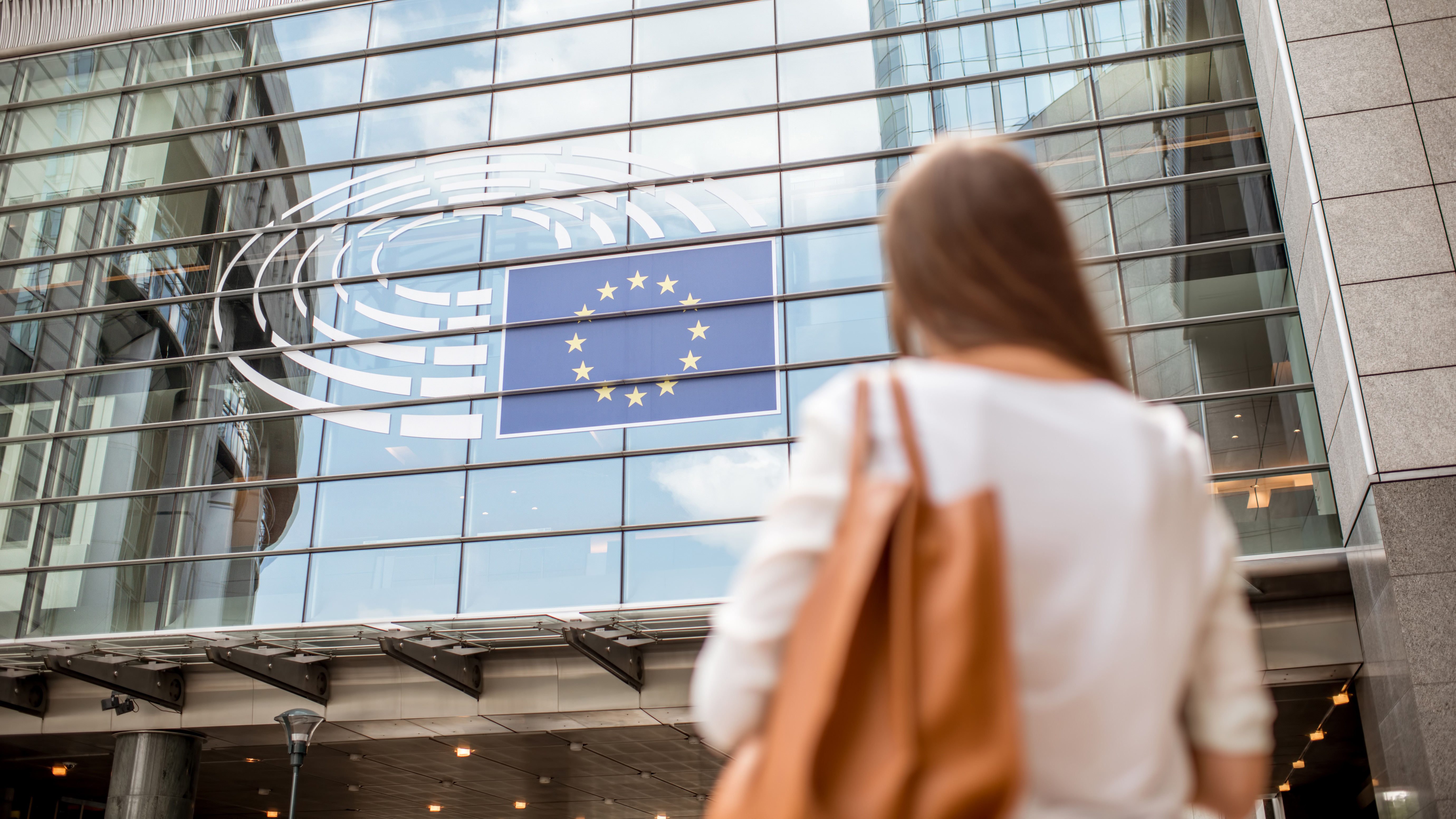 Eine Frau steht vor einem Gebäude mit einer EU Flagge
